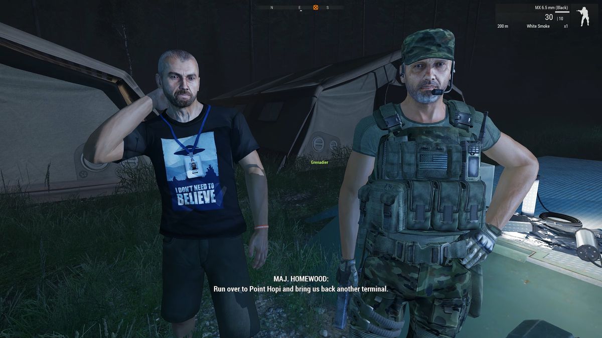 عالم يرتدي قميصًا على نمط X-Files يقول "لا أحتاج أن أصدق". كان يرتدي سراويل قصيرة ويقف بجانب جندي مسلح يحمل علمًا أمريكيًا في مقدمة جهازه.